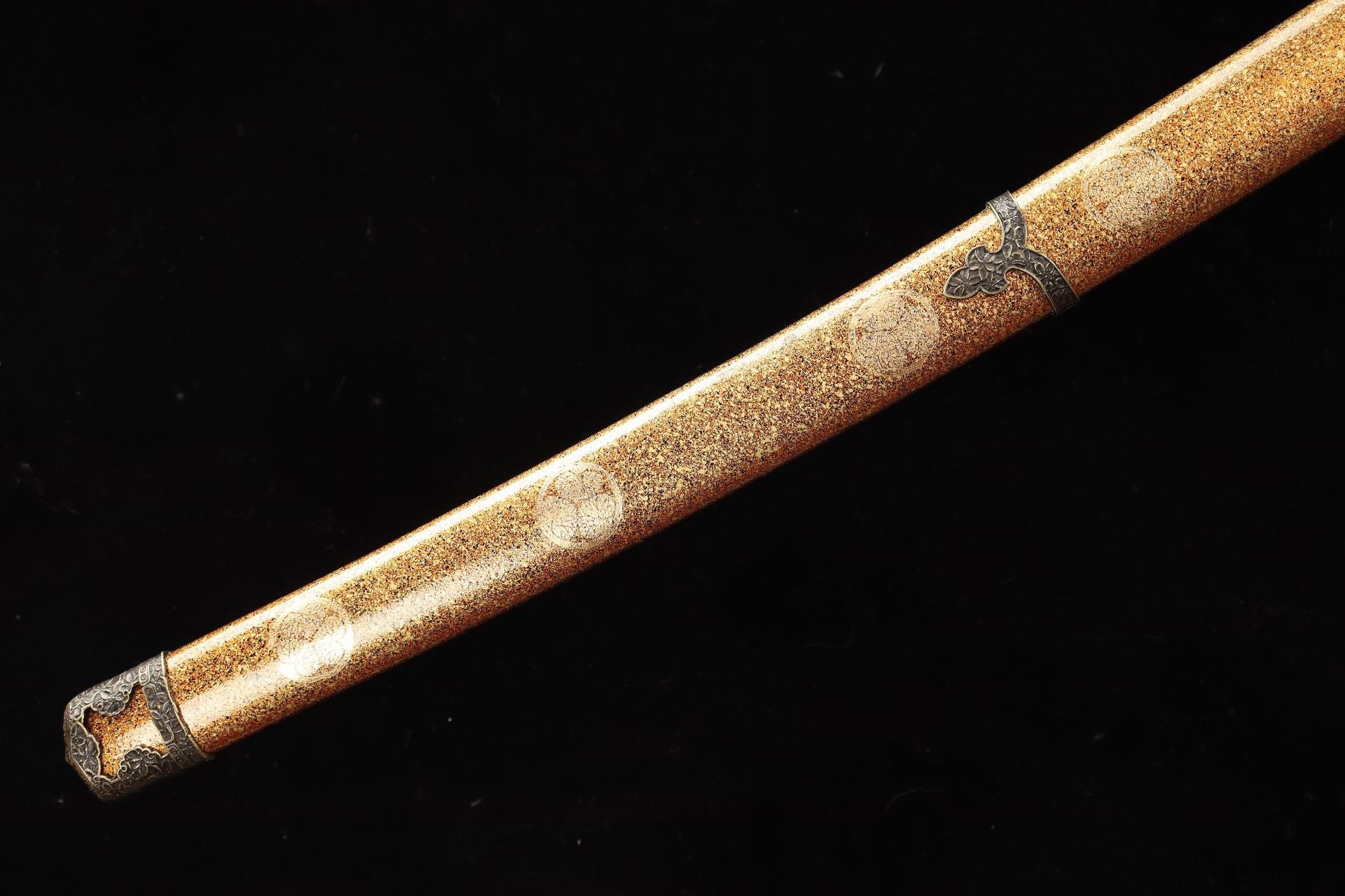 Close-up of the Nobunaga Tachi sword scabbard, featuring a gold lacquer finish with delicate embossed patterns and intricate metal fittings.