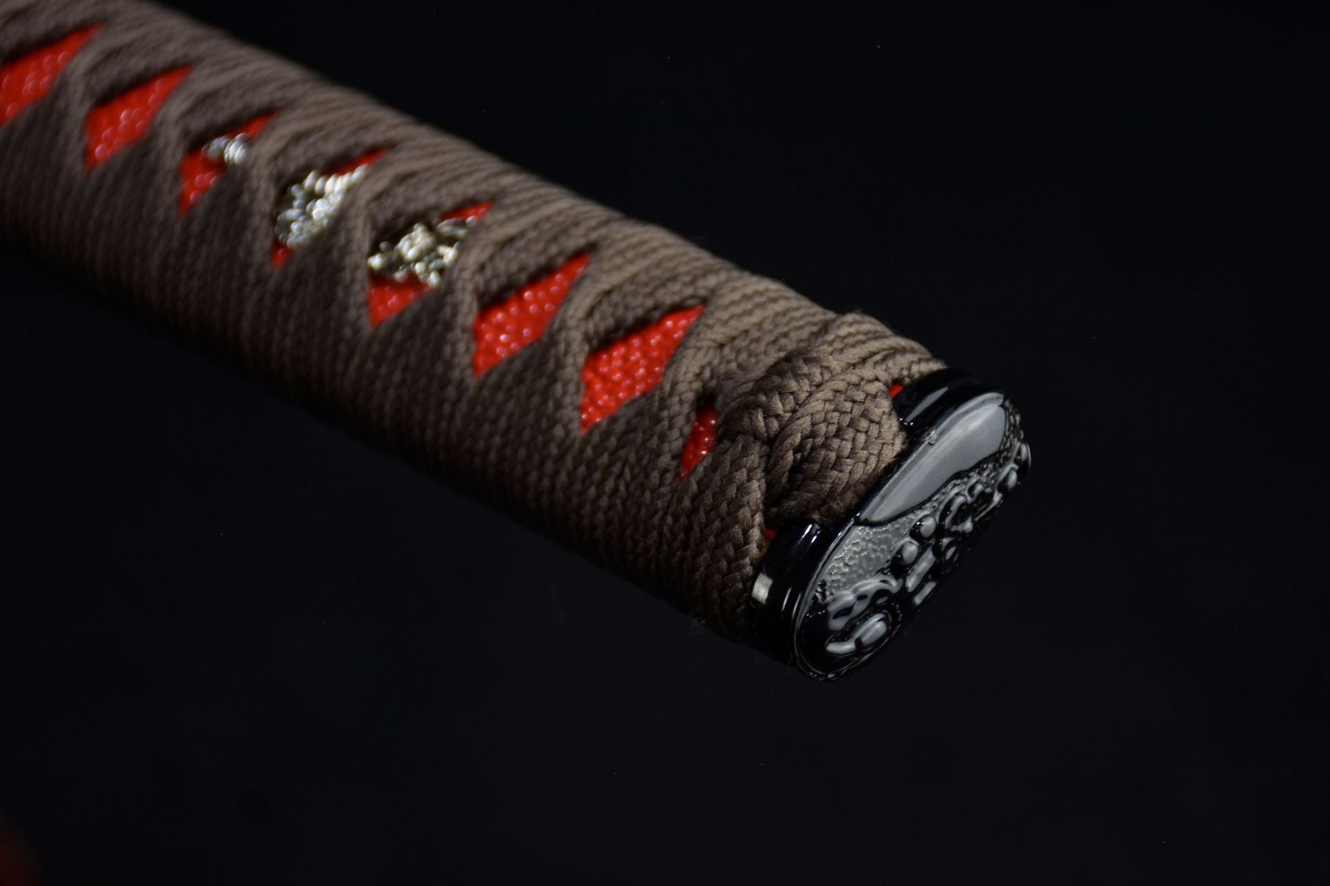A close-up of the red samurai sword handle and kashira detail
