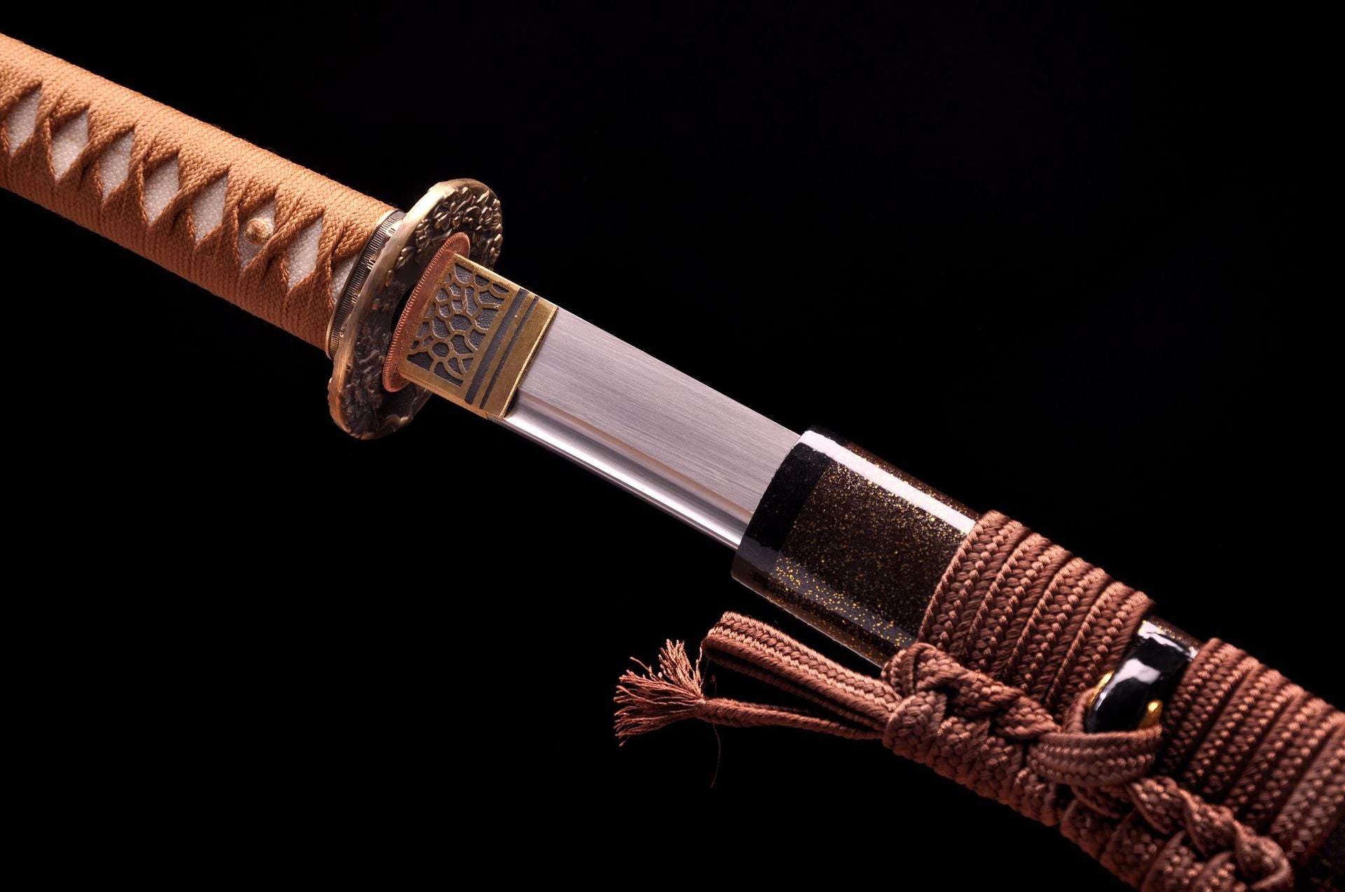 Close-up of a samurai sword showing the connection between the polished blade and floral-patterned guard, with braided sheath wrapping.