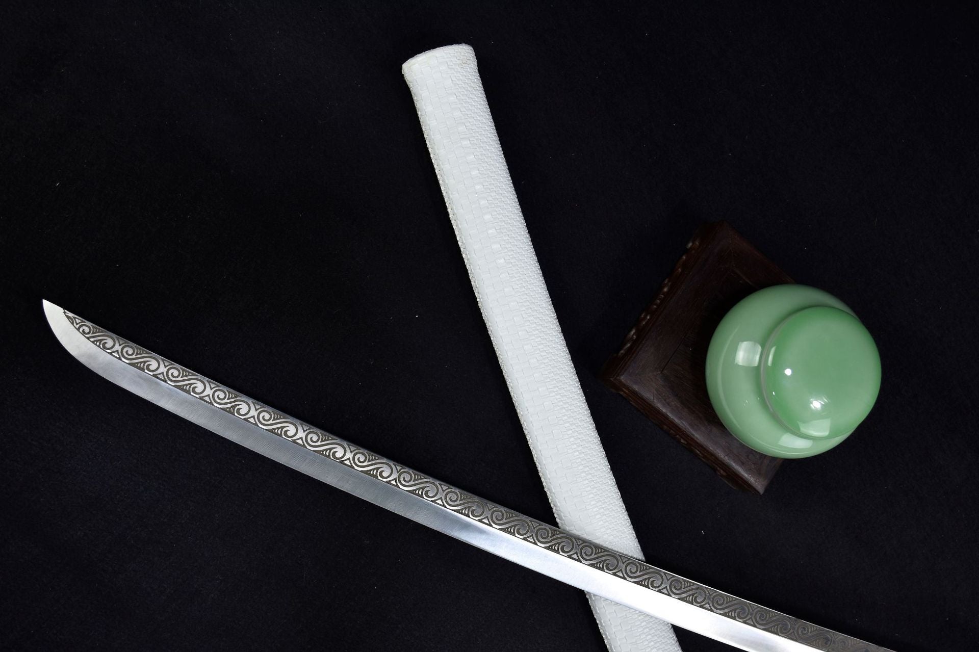 A samurai sword blade paired with a white scabbard on a black background