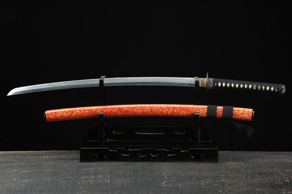 Full view of a samurai sword displayed with a red lacquer saya featuring a unique speckled design, showing the blade and tsuka with a decorative tsuba.