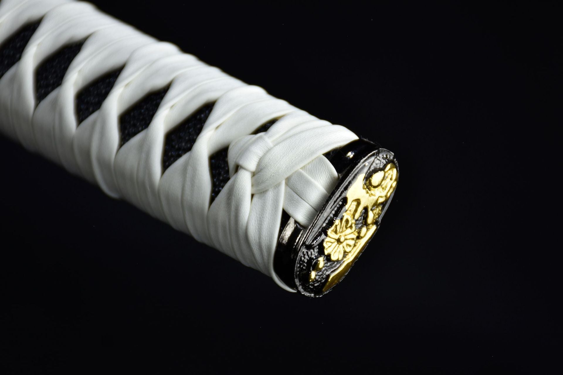 Close-up of a white samurai sword handle featuring a plum blossom kashira