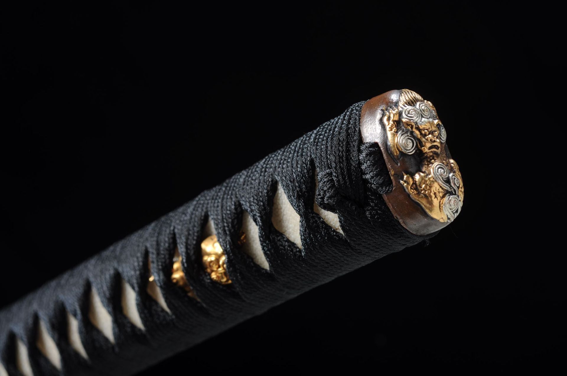 Traditional kashira of the Yuuzumi katana, ornately carved.