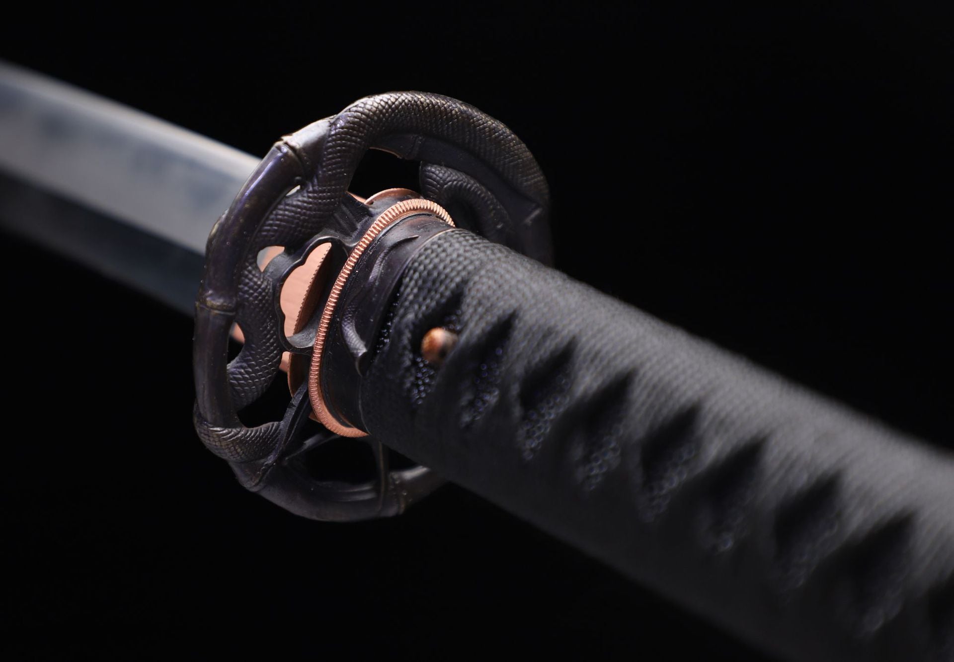 Close-up of a samurai sword guard (tsuba) featuring a serpent design, emphasizing the intricate craftsmanship.