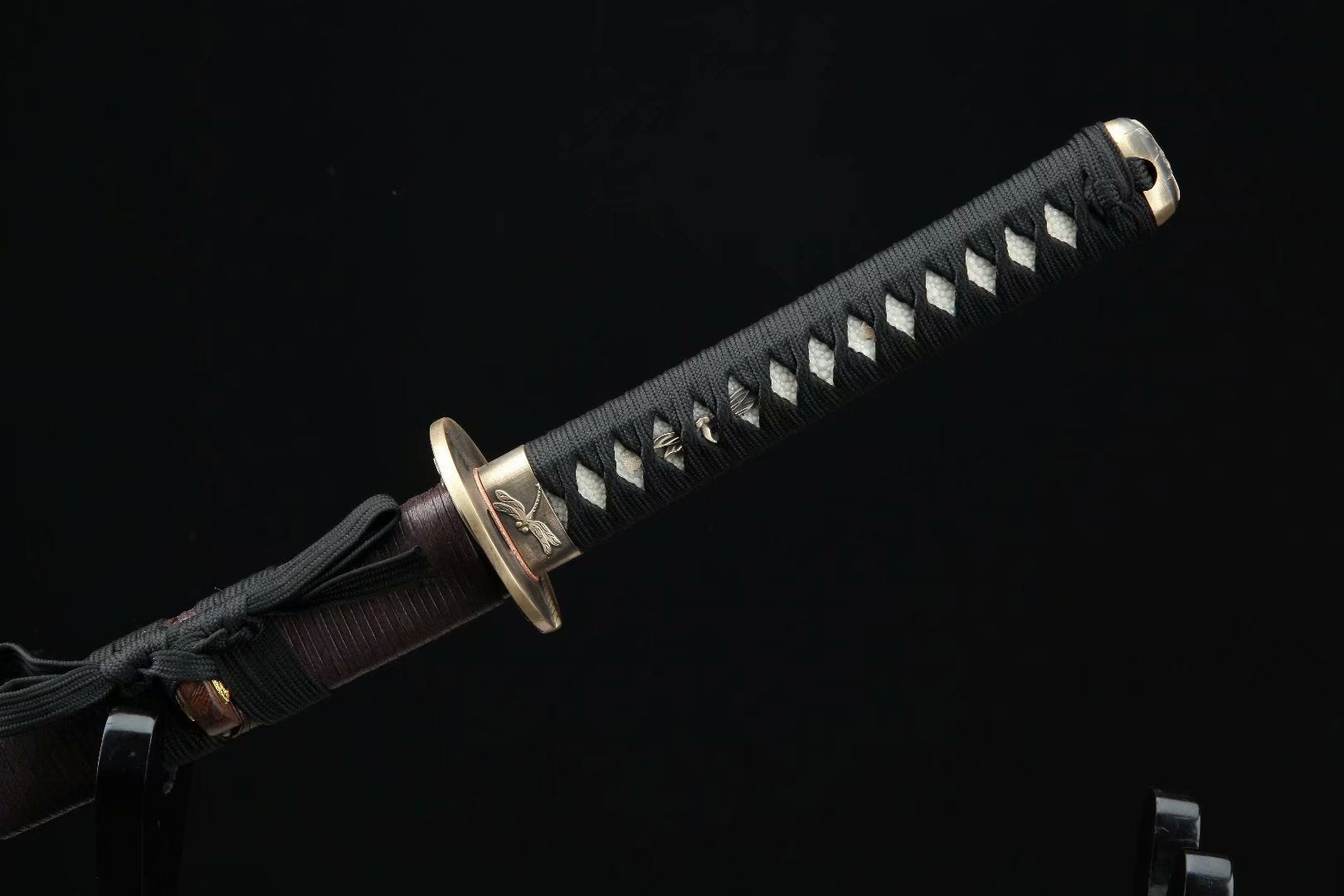 Close-up of the intricately crafted handle of the Dragonfly Wakizashi, showcasing traditional Japanese design and black cord wrap.