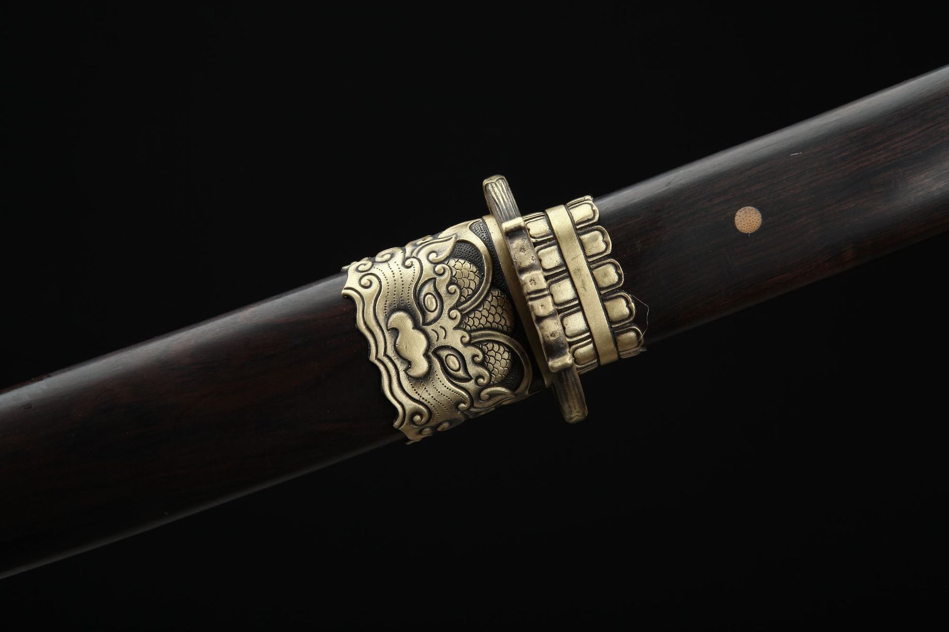 Close up of the Lion samurai sword scabbard koi-guchi featuring a traditional copper lion design on a dark ebony finish