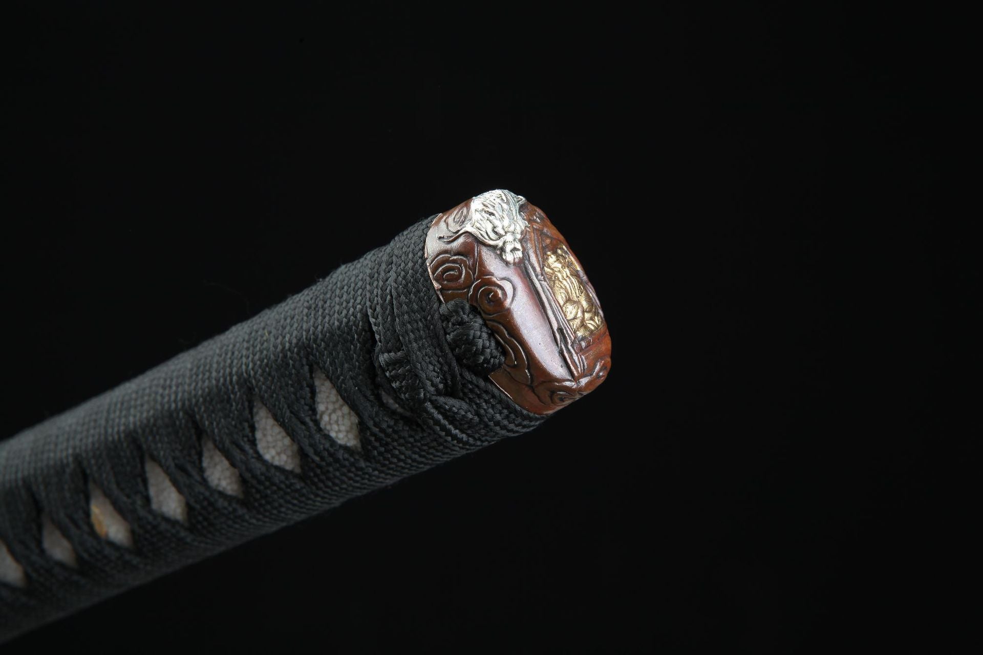 The gashira on a Loong War katana, intricately carved with a mythological battle scene featuring a dragon.