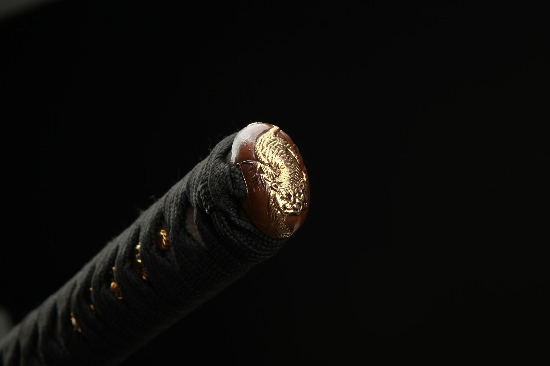 Close-up of the Mountain Lord katana's kashira featuring a detailed tiger carving, exemplifying fine metalwork.