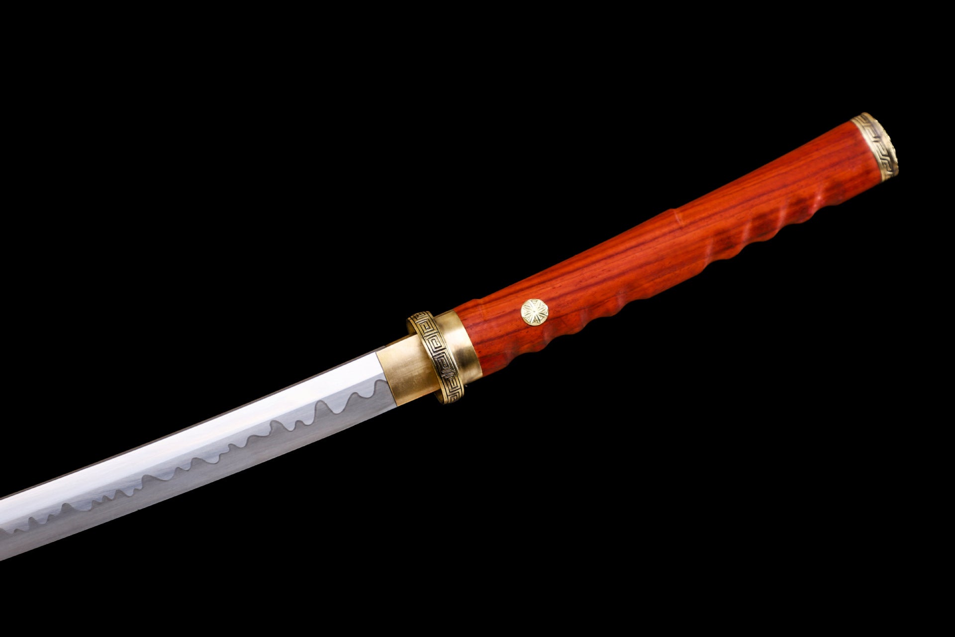 Closeup of a katana tsuka made of red rosewood with red menuki and a polished blade featuring a wavy hamon pattern.