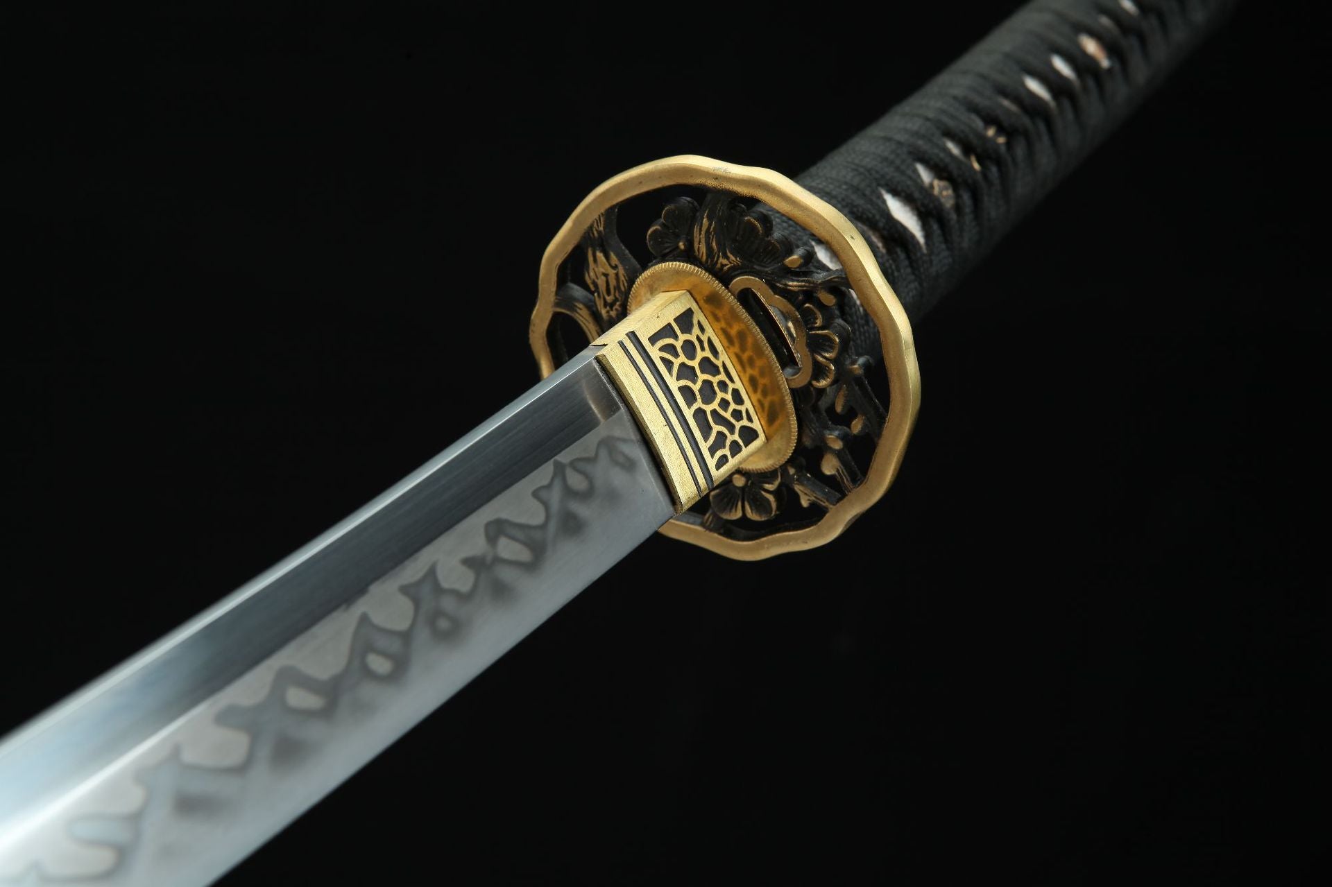 Closeup of the Sakura X katana, showing the intricate hamon on the blade and the decorative guard with detailed brass fittings.