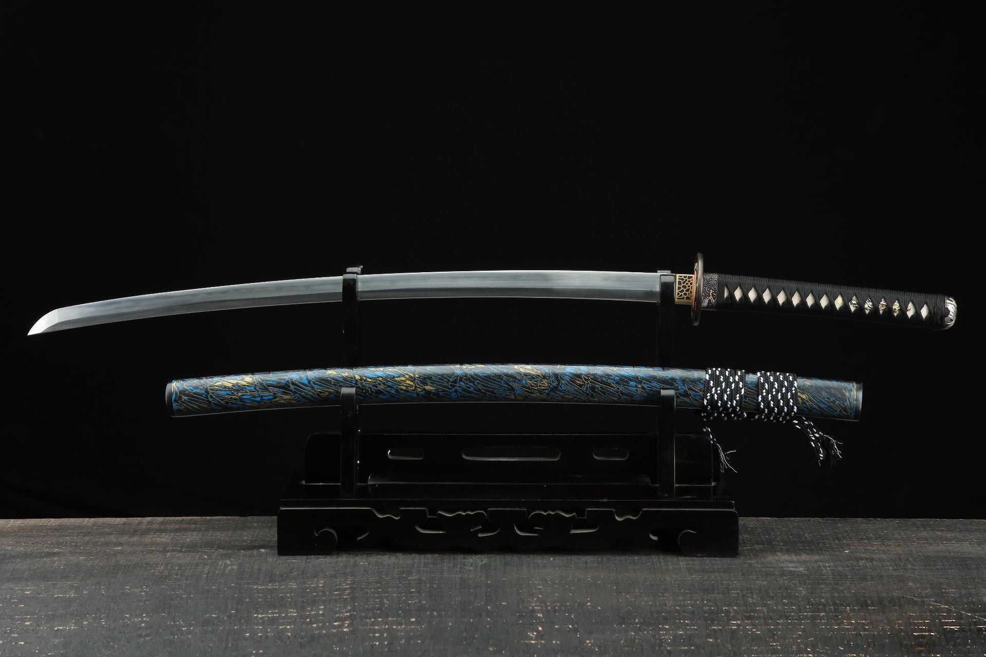 Full view of the Seiryu katana with a unique blue and gold patterned saya and a sharp, curved blade, displayed on a black wooden stand.