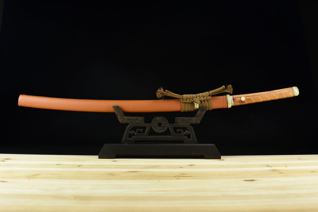 A Japanese sword displayed on a stand, featuring a tan-colored scabbard and a polished wooden handle wrapped in decorative cord.